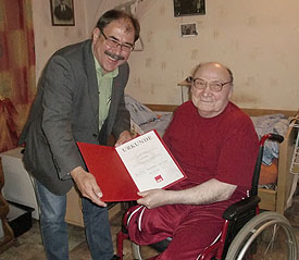 Stadtbürgermeister Günter Schnitzler gratuliert Jakob Schmitz und überreicht ihm die Urkunde mit der silbernen Ehrennade
